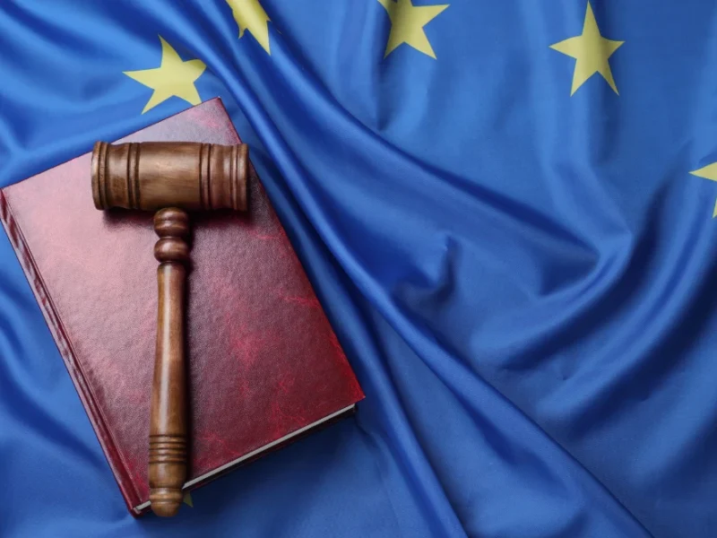 Martello del giudice e codice penale sulla bandiera europea, simbolo dell'assistenza in diritto penale dello Studio Legale Mancaniello & Partners a Parma