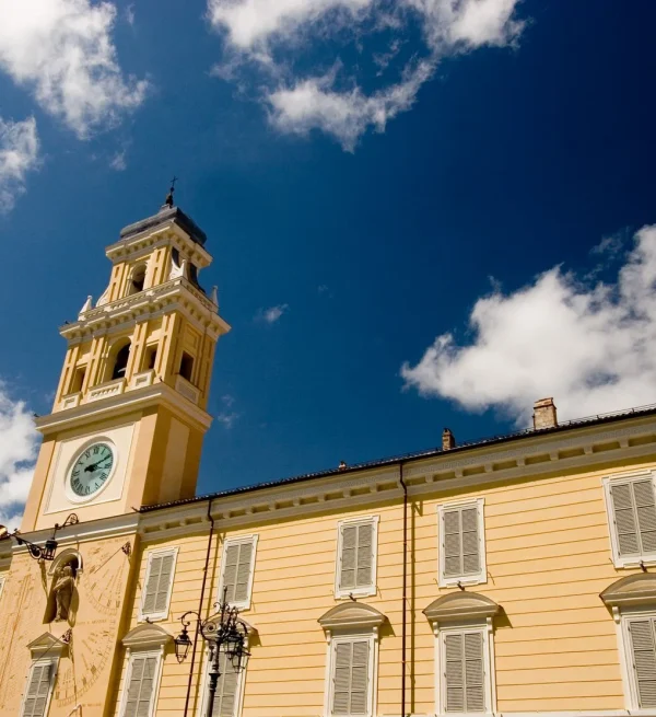 Il Palazzo del Governatore di Parma con la torre dell'orologio sotto un cielo blu, simbolo del radicamento dello studio Mancaniello & Partners nel tessuto cittadino