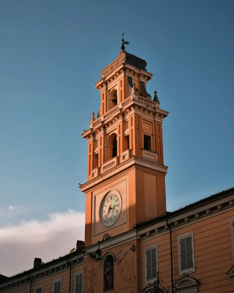 Torre con orologio del Palazzo del Governatore di Parma illuminata dalla luce del tramonto, simbolo della città in cui opera lo studio legale Mancaniello & Partners